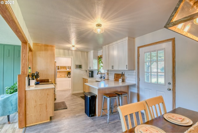 4303 SW Sheridan Ave, Pendleton, OR 97801 - kitchen with light countertops, a sink, white cabinets, light wood-style floors, and a peninsula