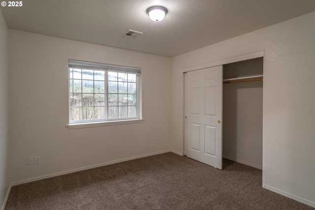 unfurnished bedroom with carpet, a textured ceiling, and a closet