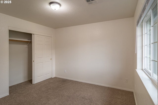 unfurnished bedroom with carpet flooring, a closet, and a textured ceiling