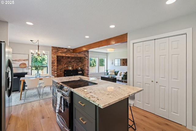 kitchen featuring light wood-style floors, recessed lighting, appliances with stainless steel finishes, and a kitchen bar