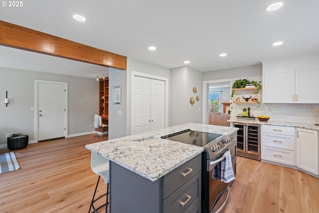 kitchen with open shelves, wine cooler, light wood-type flooring, white cabinets, and electric stove