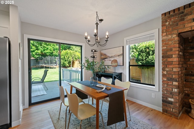 dining area with light wood-style floors, plenty of natural light, and a notable chandelier