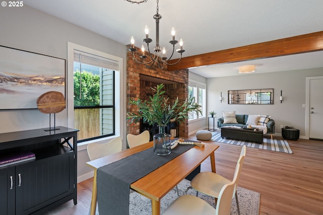 dining space featuring light wood-type flooring, baseboards, beam ceiling, and a chandelier