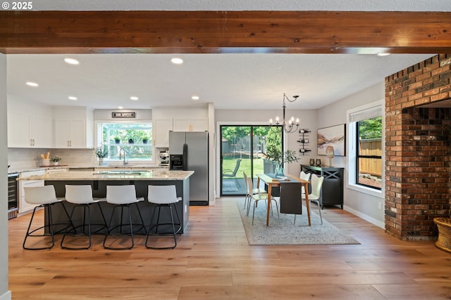 kitchen with stainless steel refrigerator with ice dispenser, plenty of natural light, and a center island