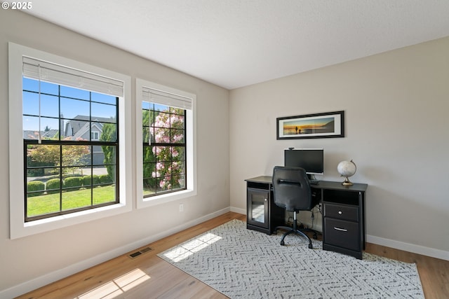 home office with baseboards, wood finished floors, and visible vents