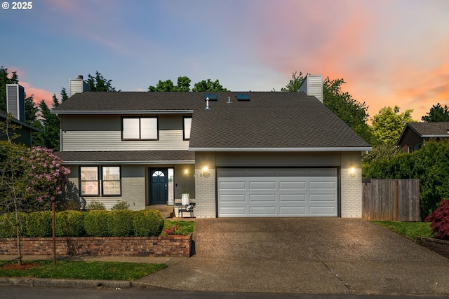 traditional home featuring fence, brick siding, a garage, a chimney, and driveway