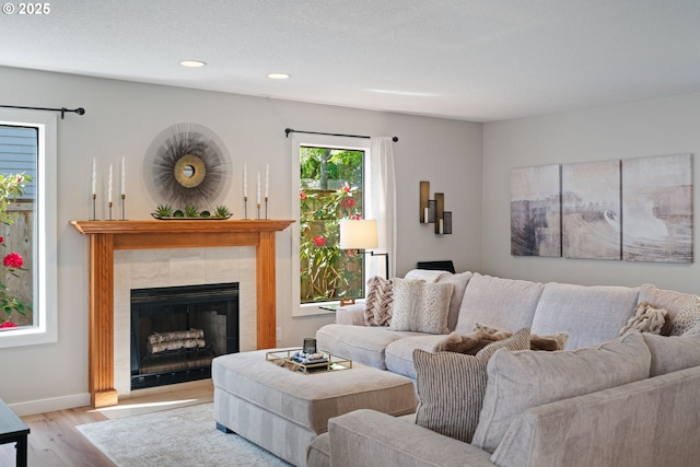 living area with recessed lighting, baseboards, wood finished floors, and a tiled fireplace
