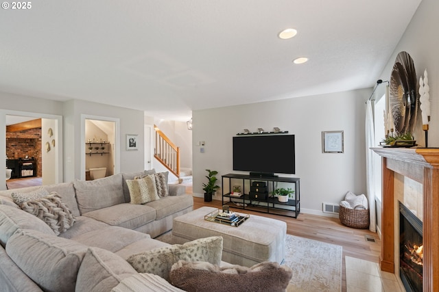 living room featuring light wood finished floors, a fireplace, stairs, recessed lighting, and visible vents