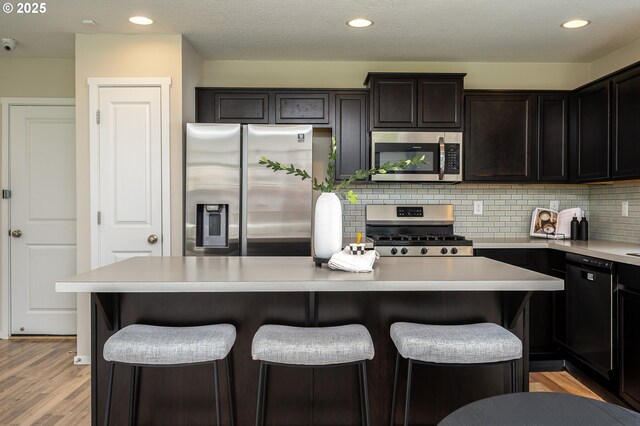 505 NE 138th Pl, Vancouver, WA 98684 - kitchen featuring appliances with stainless steel finishes, light countertops, a kitchen breakfast bar, decorative backsplash, and light wood-style floors