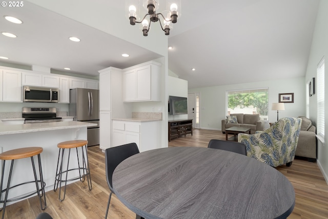 dining area with light wood-type flooring, recessed lighting, lofted ceiling, a chandelier, and baseboards