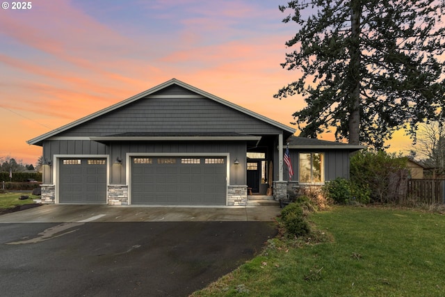 view of front of house with board and batten siding, a front yard, stone siding, and driveway