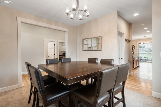 dining space with an inviting chandelier, light wood-style flooring, and baseboards