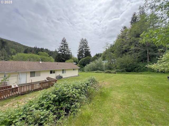 94031 Green Acres Ln, Coos Bay, OR 97420 - view of grassy yard featuring a wooden deck and central air condition unit