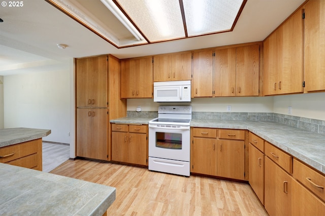 kitchen featuring light countertops, light wood-type flooring, brown cabinets, and white appliances