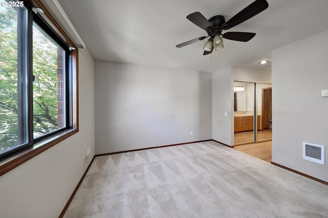 spare room with baseboards, a wealth of natural light, visible vents, and light colored carpet