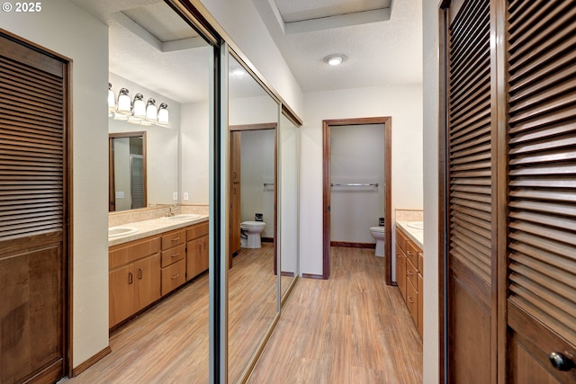 bathroom with toilet, a closet, and wood finished floors