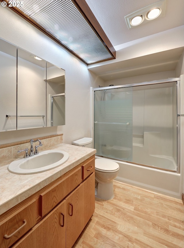 full bathroom with toilet, shower / bath combination with glass door, vanity, and wood finished floors