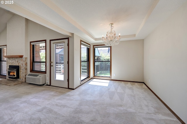 interior space featuring a wall mounted air conditioner, carpet, a chandelier, a raised ceiling, and baseboards