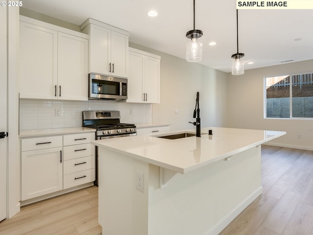 kitchen with light wood-style floors, appliances with stainless steel finishes, backsplash, and a sink