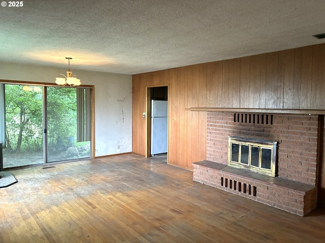 33962 Church Rd, Warren, OR 97053 - unfurnished living room with a chandelier, a textured ceiling, a fireplace, wood finished floors, and wooden walls