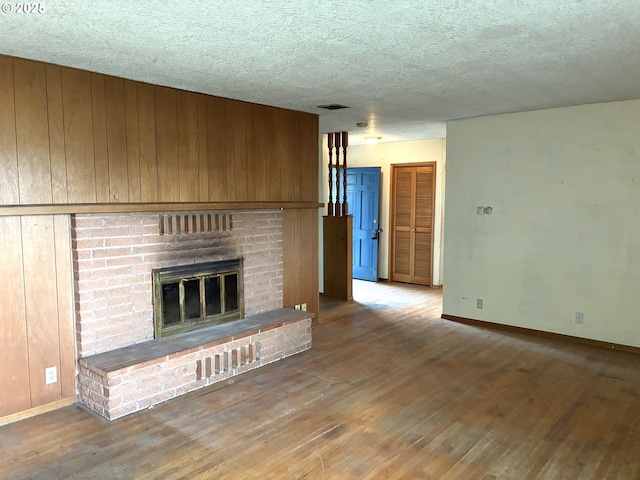 33962 Church Rd, Warren, OR 97053 - unfurnished living room featuring hardwood / wood-style flooring, a fireplace, a textured ceiling, and wood walls