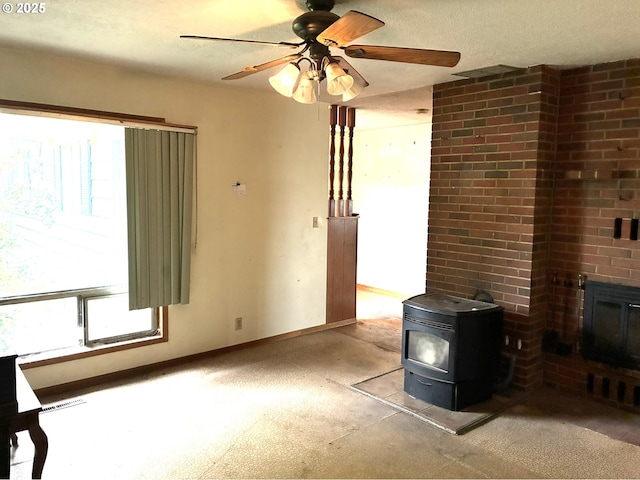 33962 Church Rd, Warren, OR 97053 - unfurnished living room with plenty of natural light, a wood stove, a ceiling fan, a textured ceiling, and light colored carpet