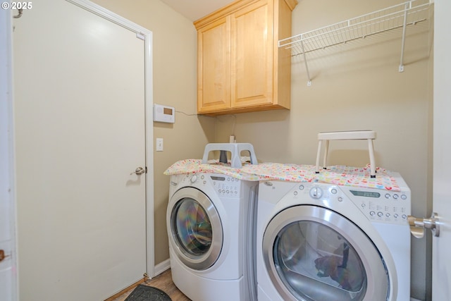 laundry room with cabinet space, washing machine and clothes dryer, and wood finished floors