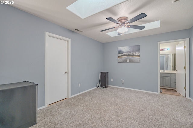 unfurnished bedroom with a skylight, light colored carpet, visible vents, and baseboards