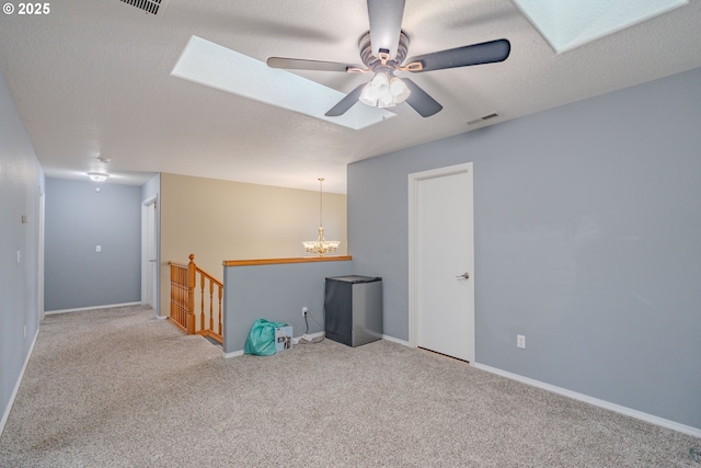 spare room with baseboards, visible vents, light colored carpet, a textured ceiling, and ceiling fan with notable chandelier