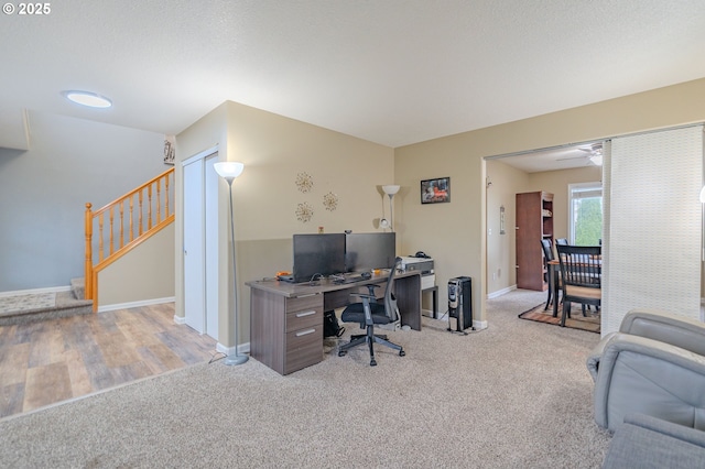 office area with light carpet, baseboards, and a textured ceiling