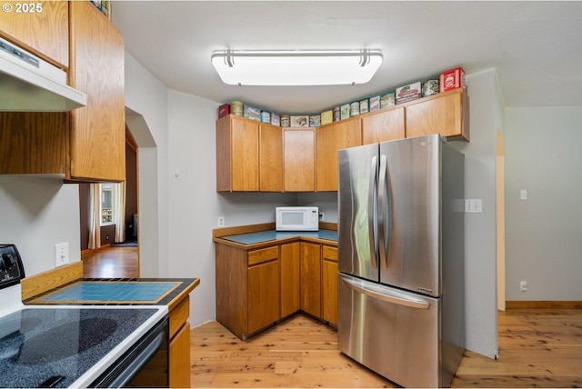 7980 Kilchis River Rd, Tillamook, OR 97141 - kitchen with freestanding refrigerator, white microwave, electric range oven, and light wood-type flooring
