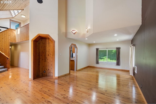7980 Kilchis River Rd, Tillamook, OR 97141 - unfurnished living room featuring a towering ceiling, hardwood / wood-style floors, arched walkways, stairway, and baseboards