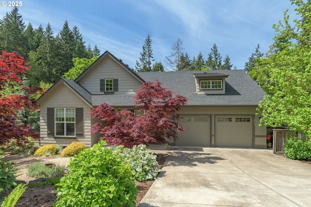 traditional-style house with a garage, a shingled roof, and concrete driveway