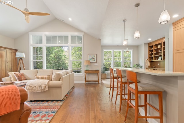 living area with light wood-style flooring, ceiling fan, vaulted ceiling, recessed lighting, and baseboards