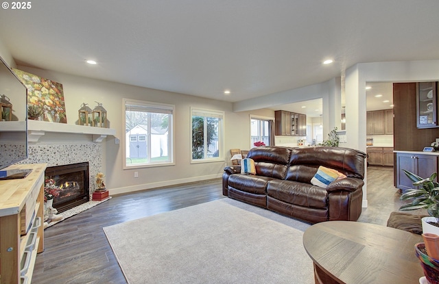 living room with a tiled fireplace, a wealth of natural light, and dark hardwood / wood-style flooring