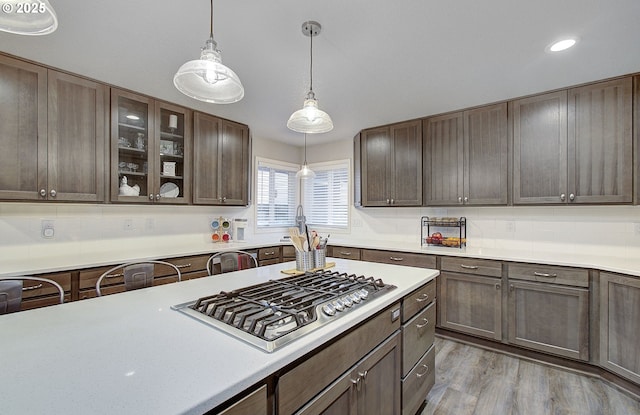 kitchen with dark brown cabinetry, sink, light wood-type flooring, pendant lighting, and stainless steel gas stovetop