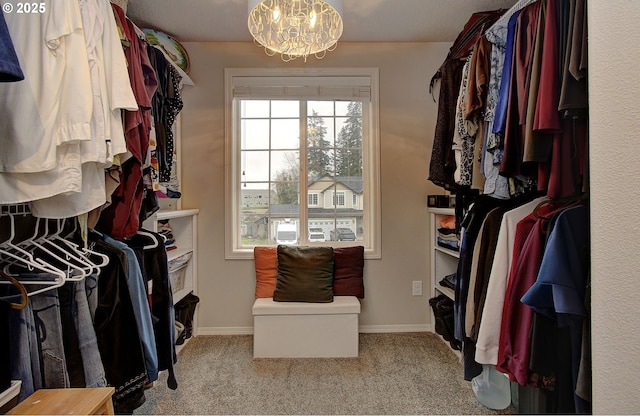 walk in closet featuring a notable chandelier and light colored carpet