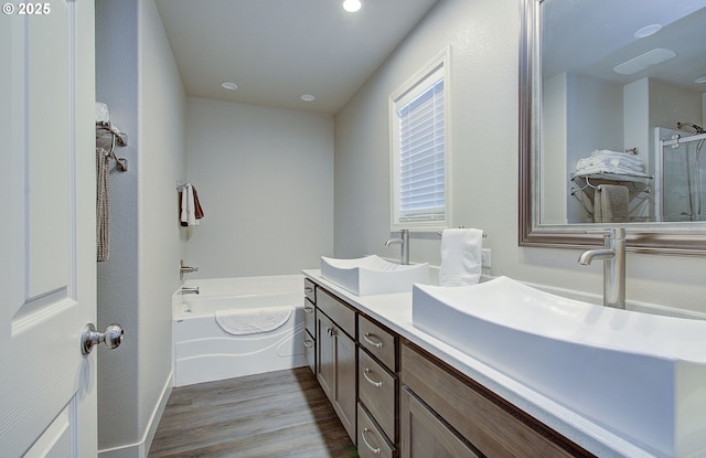 bathroom with wood-type flooring, independent shower and bath, and vanity