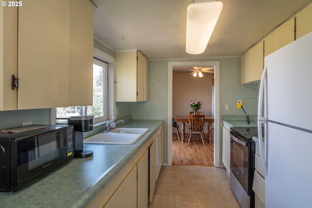 164 Pippin Ave, Roseburg, OR 97471 - kitchen with a sink, black microwave, electric range, cream cabinetry, and freestanding refrigerator