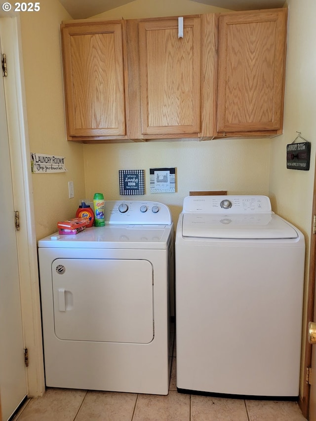 clothes washing area with light tile patterned flooring, cabinet space, and washer and clothes dryer