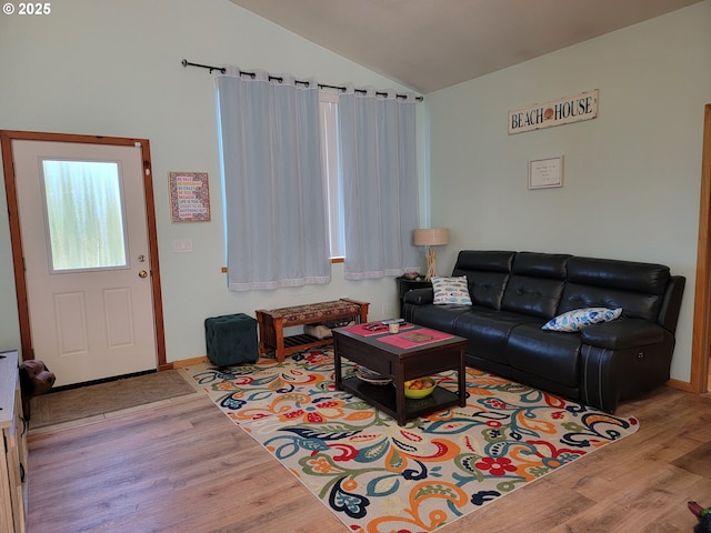 living area with baseboards, vaulted ceiling, and wood finished floors