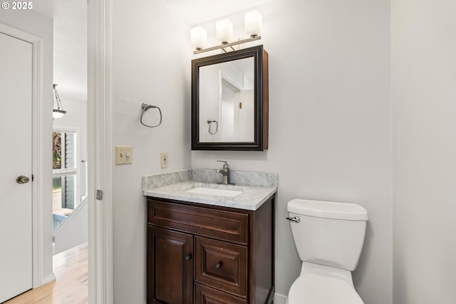 half bathroom featuring vanity, toilet, and wood finished floors