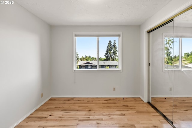 unfurnished bedroom with light wood-style flooring, a closet, and baseboards