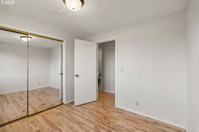 unfurnished bedroom with wood finished floors, a closet, and baseboards
