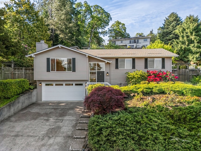 view of front of property featuring an attached garage, fence, asphalt driveway, and a chimney