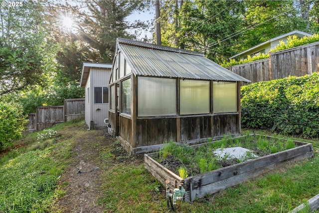 view of greenhouse featuring a vegetable garden and a fenced backyard