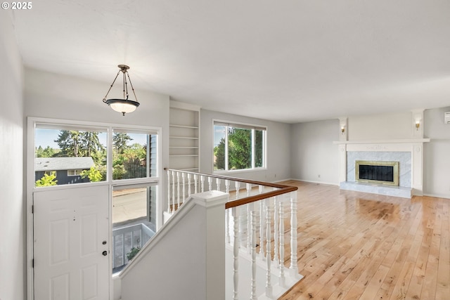 foyer entrance with light wood-style flooring, a premium fireplace, and baseboards