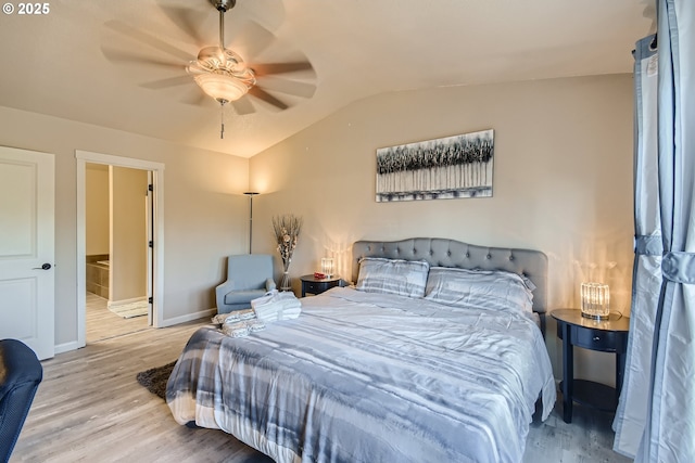 bedroom with ceiling fan, vaulted ceiling, ensuite bath, and light wood-type flooring