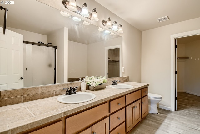 bathroom featuring vanity, toilet, hardwood / wood-style floors, and a shower with shower door