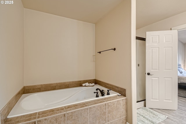 bathroom with lofted ceiling and tiled bath